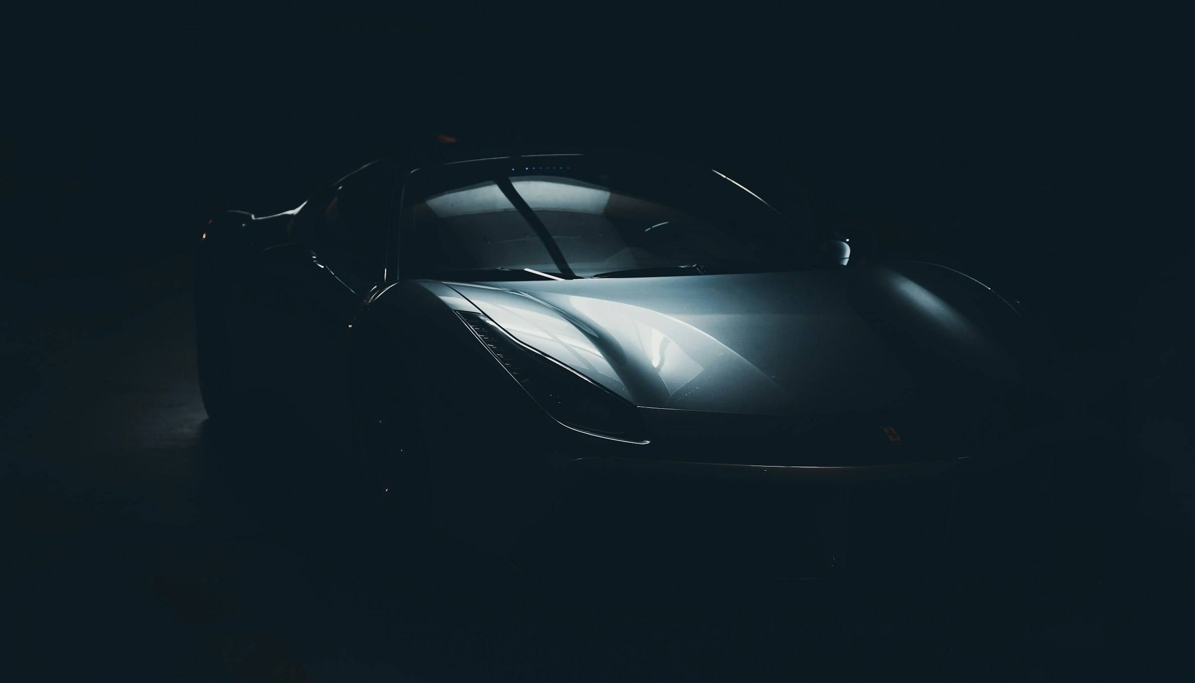 Black sports car silhouetted under soft studio light