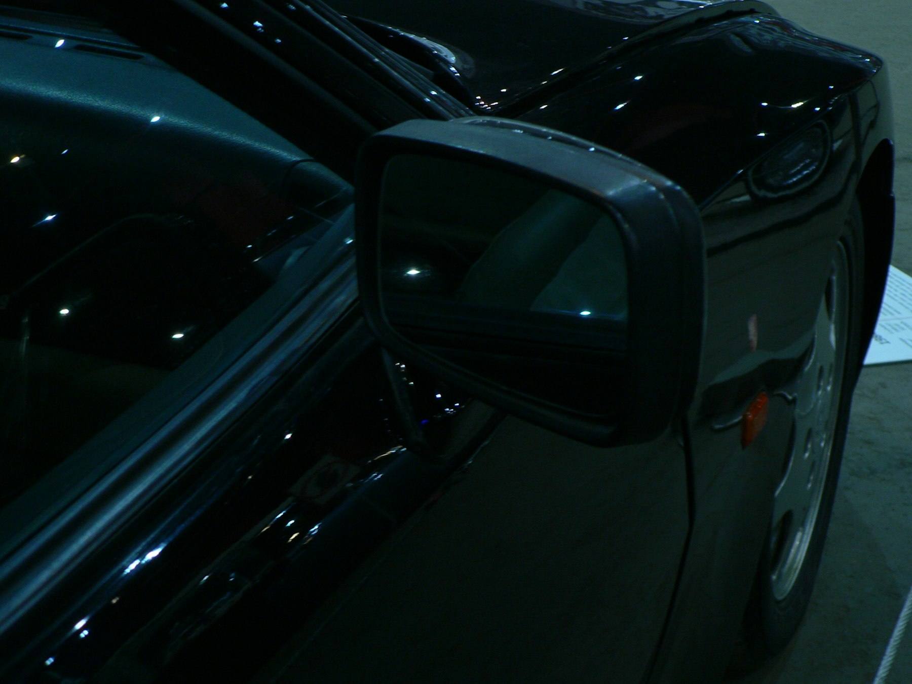 Mirror-finish black paint reflecting the sky around a side mirror